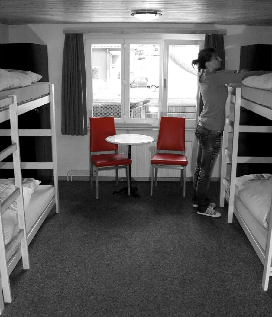 A student standing beside a bunk bed in a shared room